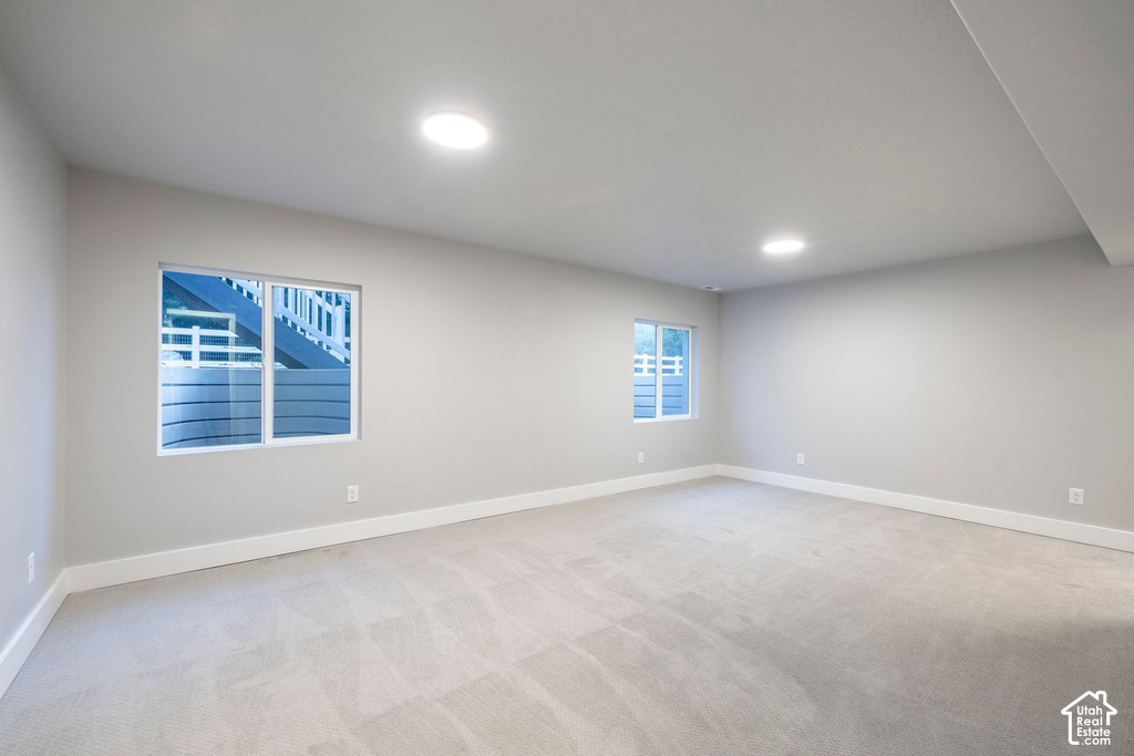Spacious room featuring light-toned carpet flooring, neutral painted walls, and bright white baseboards