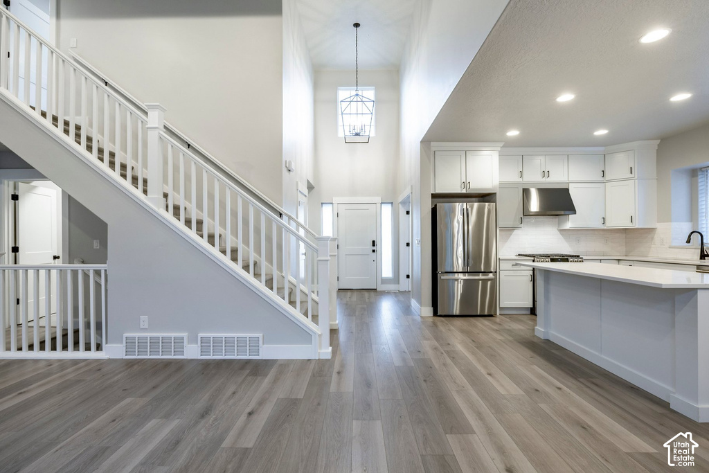 Entryway with a two-story ceiling and contemporary chandelier, featuring wood-finish flooring throughout the main level