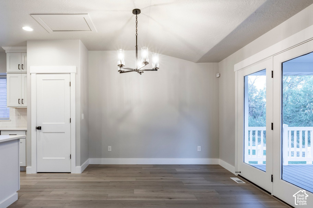 Dining area featuring French doors opening to an exterior deck, wood-finish flooring, a modern chandelier, and recessed lighting