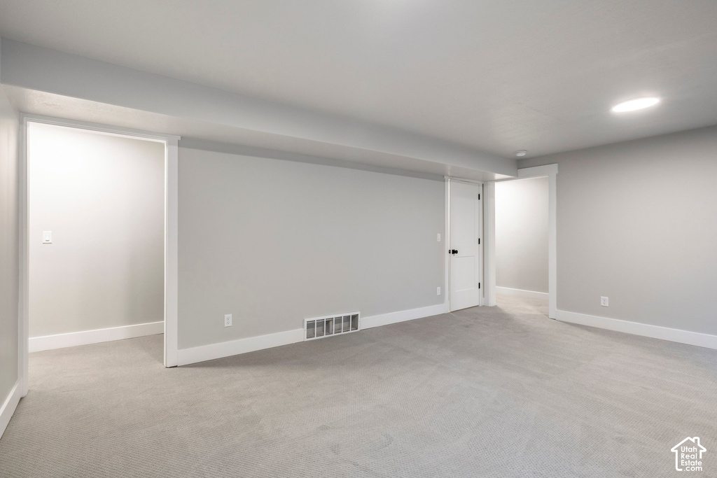 Spacious interior room featuring light grey carpeting, white trim, and light grey painted walls