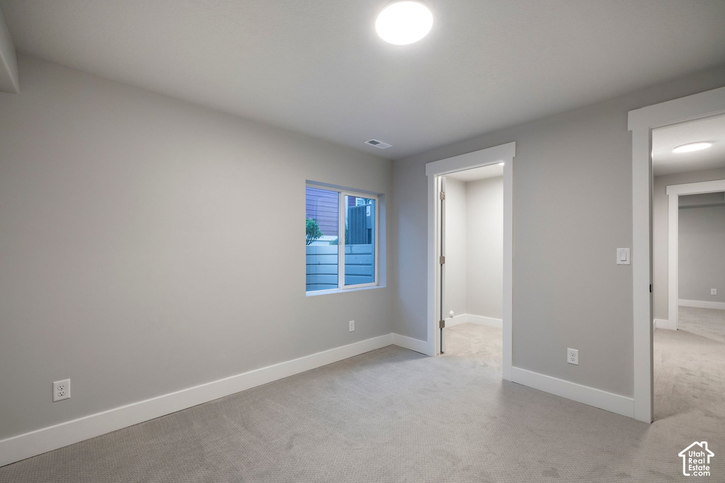 Bright secondary bedroom with neutral gray walls, recessed ceiling lighting, and neutral-tone carpet flooring