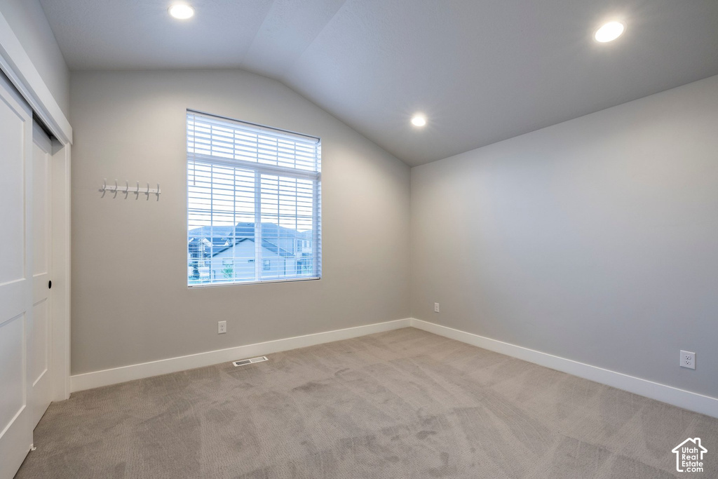 Vaulted ceiling room featuring recessed lighting, a window with horizontal blinds, light-toned carpeting, and a sliding barn door style closet