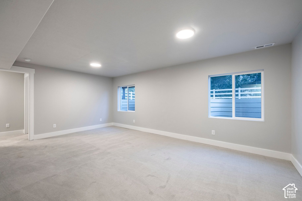 Bright and spacious room featuring recessed ceiling lighting, neutral wall finishes, light-colored flooring, and multiple windows with blue shutters providing natural illumination