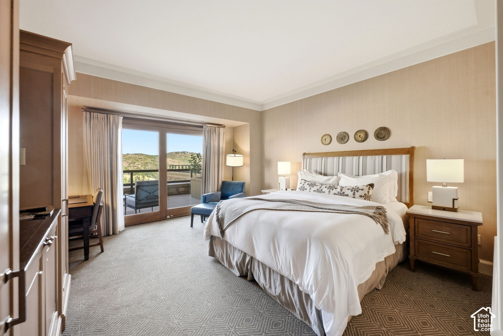 Spacious room with a private balcony, wood-finish sliding glass doors, built-in cabinetry, patterned carpet, and crown molding