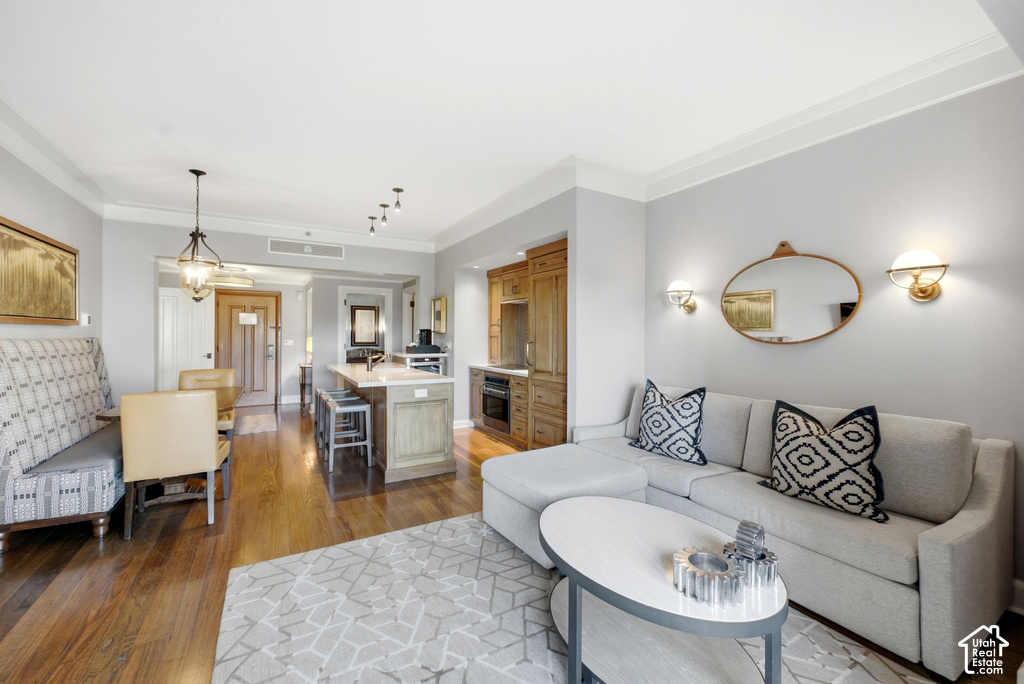 Hardwood flooring throughout the main living areas, crown molding, kitchen island with seating, built-in cabinetry, and integrated appliances