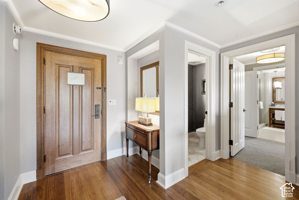 Hardwood flooring entry with crown molding, panel doors, and recessed lighting
