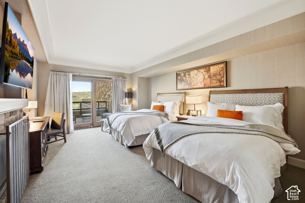 Spacious room featuring patterned carpeting, twin beds with upholstered headboards, and a glass-paned door opening to an exterior balcony