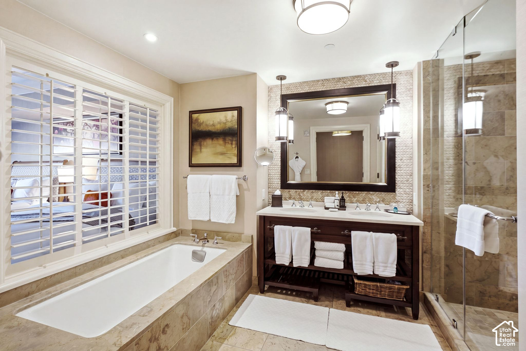 Spacious bathroom featuring a built-in soaking tub with stone surround, a dual vanity with undermount sinks, and a glass-enclosed shower with stone tile