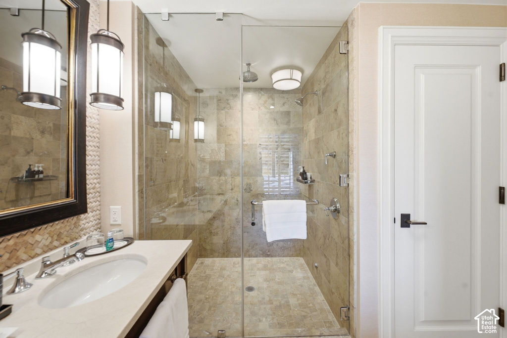 Full-glass shower enclosure with natural stone tile surrounds and a built-in bench
