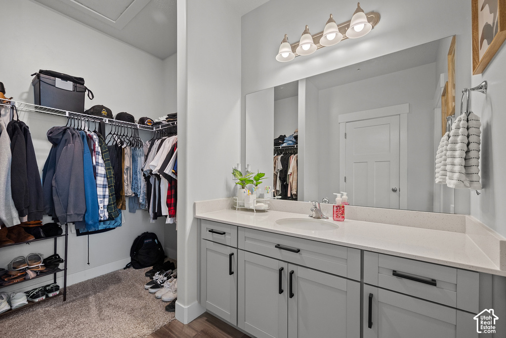 Spa-inspired primary bathroom featuring a gray vanity with black hardware, white quartz countertop, and an expansive framed mirror illuminated by pendant lighting