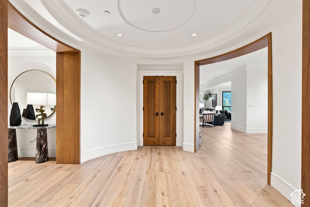 Elegant foyer showcasing curved architectural details, warm wood-finish flooring throughout, and seamless sightlines enhanced by arched doorways with wood-trim framing