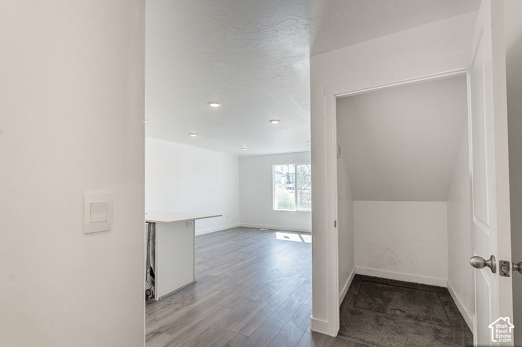 Modern open-concept living space featuring wood-finish flooring, recessed ceiling lighting, and clean white walls with minimal trim detailing
