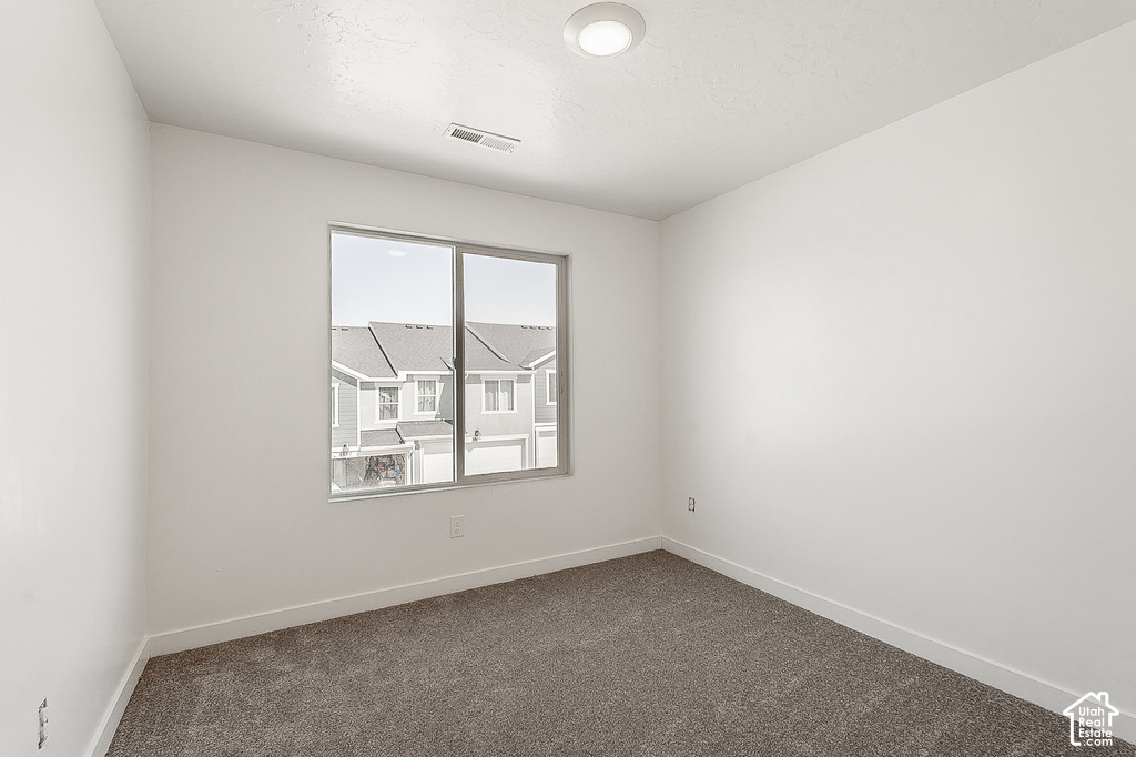 Room featuring a window with a neighborhood backdrop, white walls, gray carpet, and a recessed ceiling light