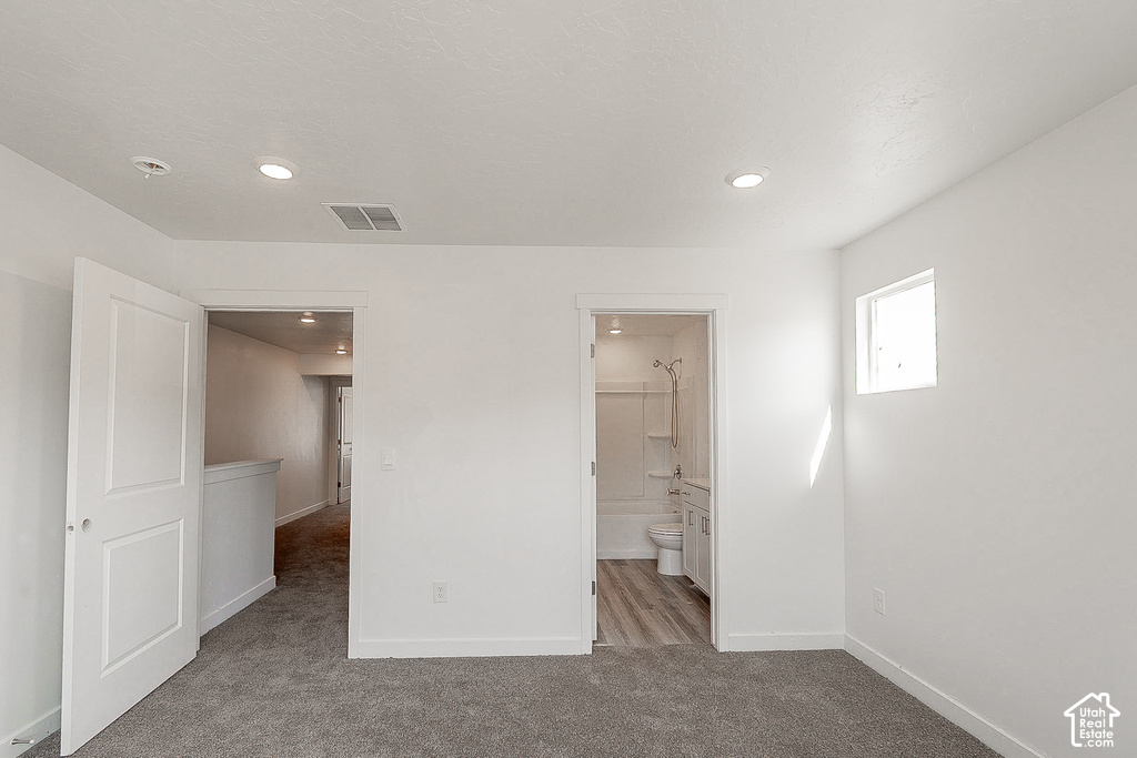Bright primary bedroom with recessed ceiling lighting, multiple entry points, and direct access to an ensuite bathroom featuring tile shower surround