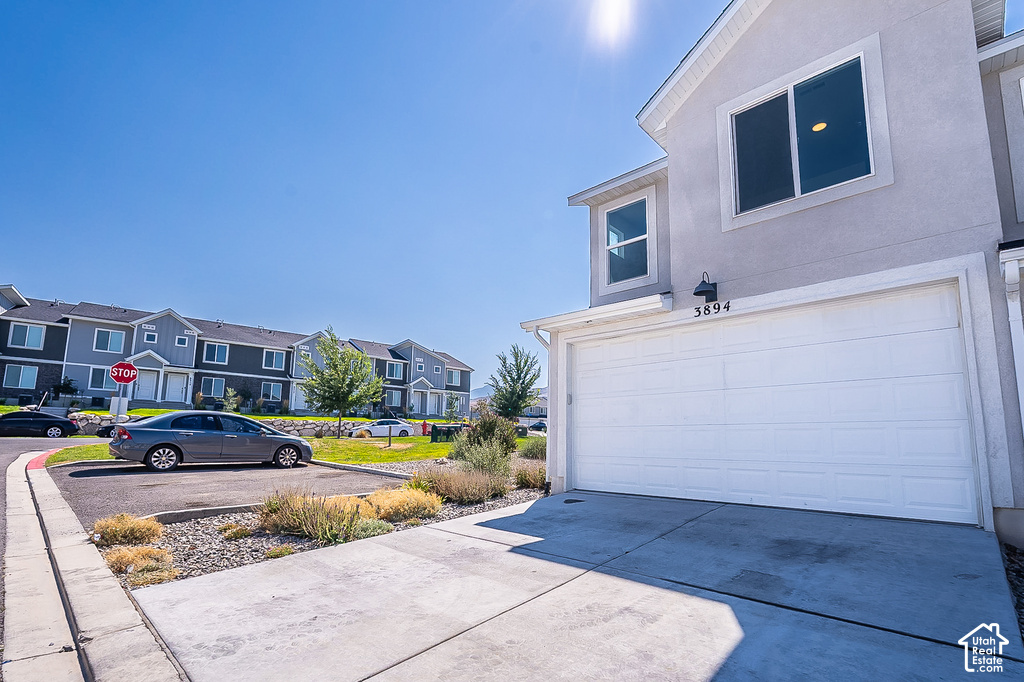 Modern two-story residence featuring a spacious three-car garage with white paneled doors, wide concrete driveway, and clean architectural lines