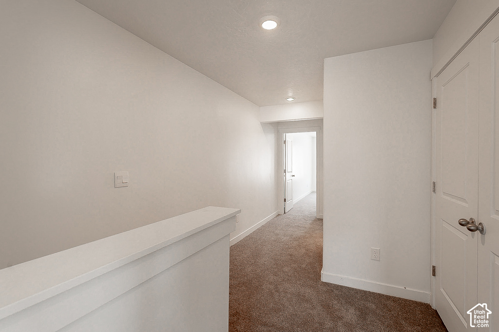 Hallway featuring recessed lighting, light neutral paint, white trim, and brown carpet flooring