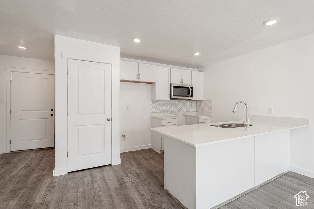 Modern kitchen featuring a spacious island with white cabinetry, stainless steel appliances including a microwave, quartz countertops, and a polished nickel faucet