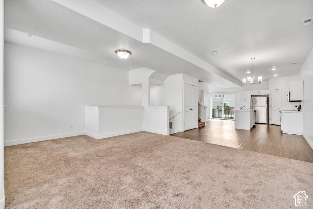 Open-concept living area featuring a neutral carpeted floor, white walls, and a recessed ceiling light