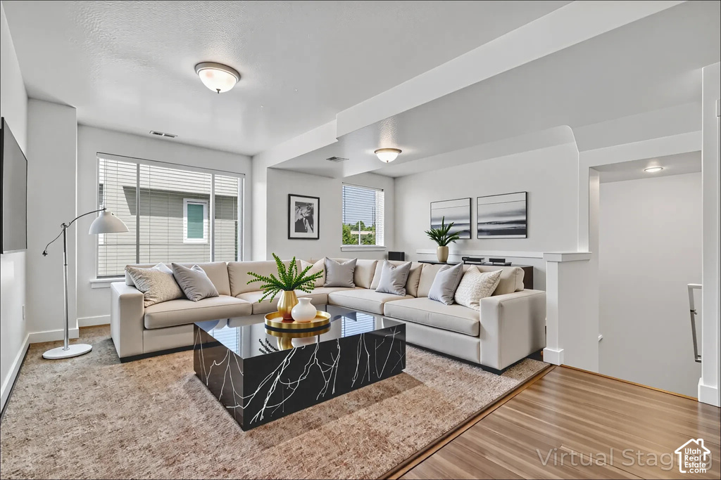 Bright, open living area showcasing a sectional sofa arrangement, black marble-topped coffee table, and neutral area rug anchoring the space
