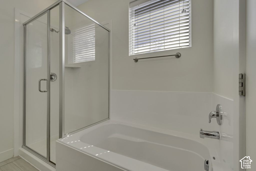 Full bathroom featuring a shower enclosure with a glass door, a built-in bathtub, a window with blinds, and chrome fixtures