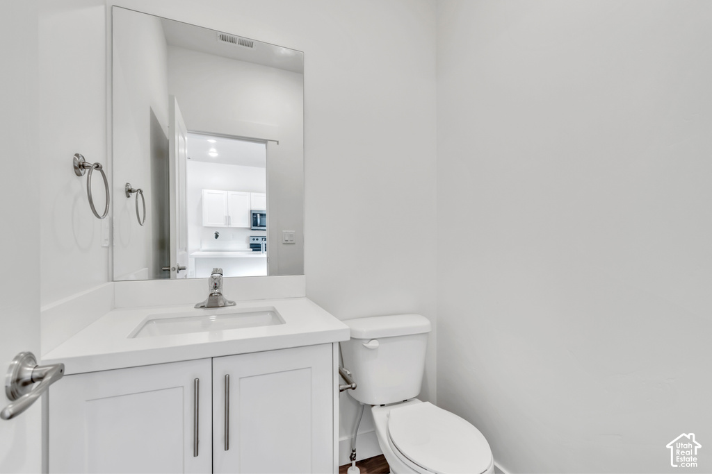 Modern powder room featuring a white vanity with integrated sink, chrome faucet, wall-mounted mirror, and white toilet