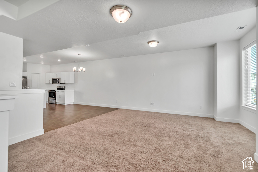Open-concept living area featuring a neutral carpeted floor, white walls, and a large window with blinds