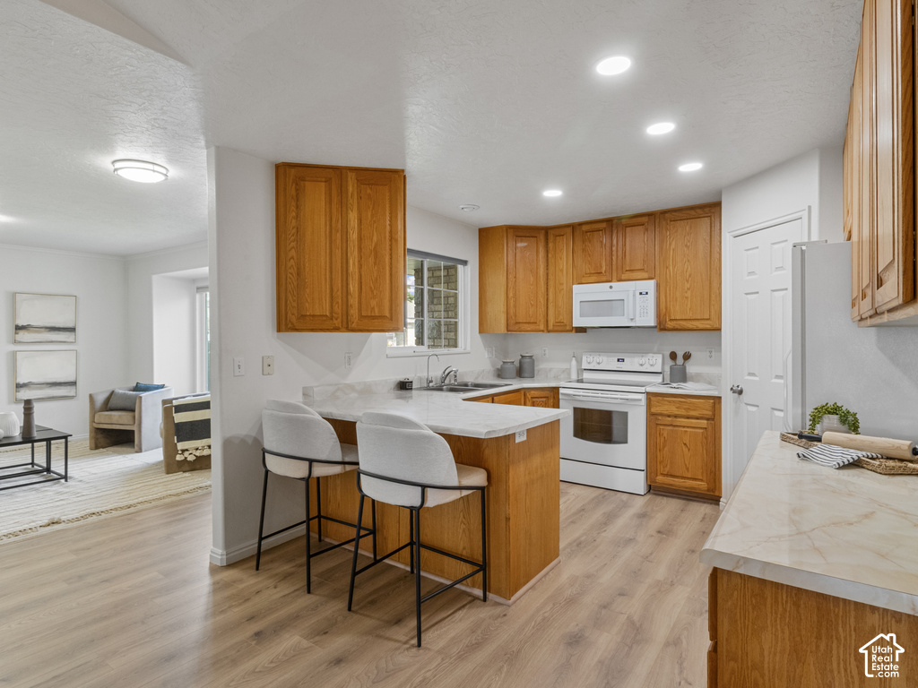 Kitchen featuring wood cabinetry, light-toned countertops, a built-in range, and wood-finish flooring