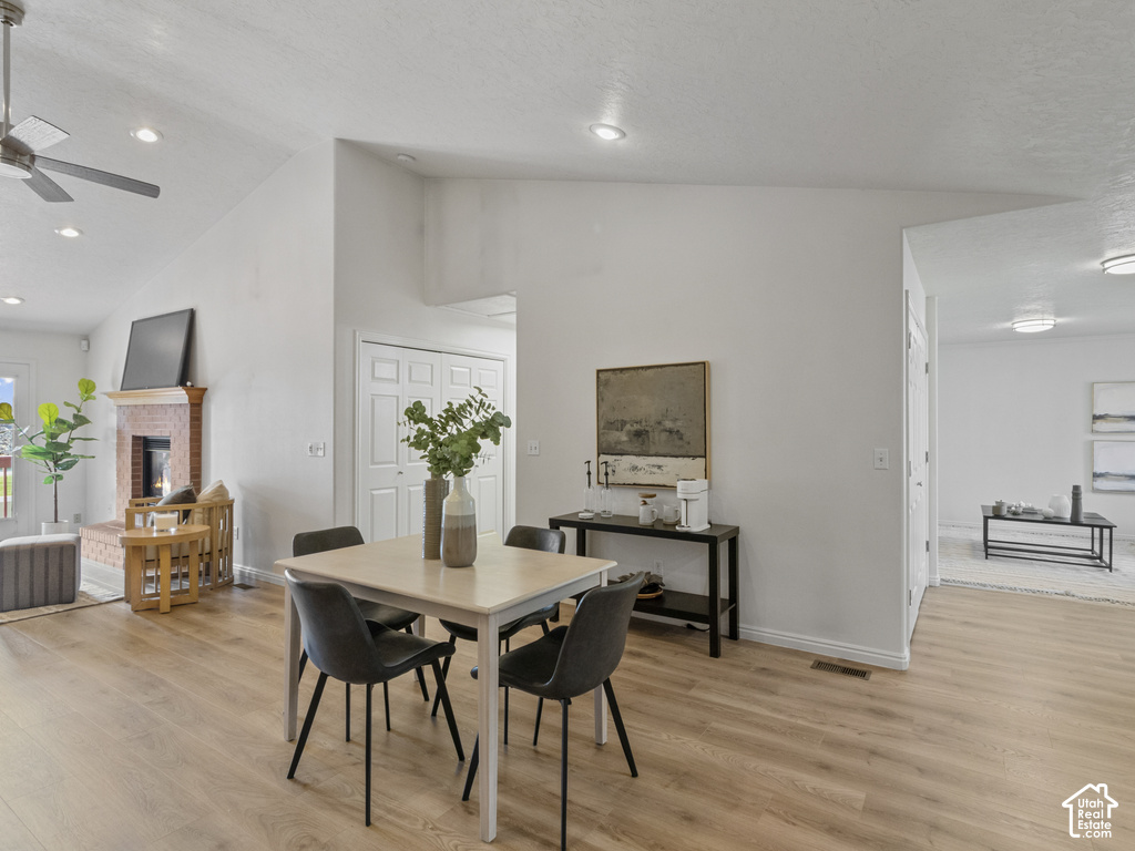 Wood-finish flooring throughout, vaulted ceilings, recessed lighting, and a brick fireplace