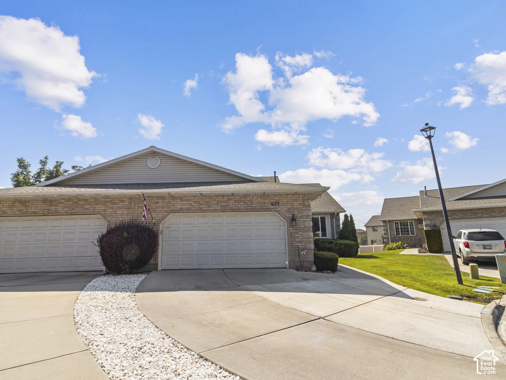 Brick facade, two-car garage, concrete driveway, white stone landscaping, street lamp
