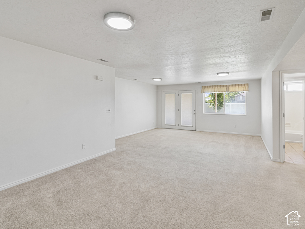 Spacious room with light-colored carpeting, white walls, and multiple ceiling-mounted light fixtures