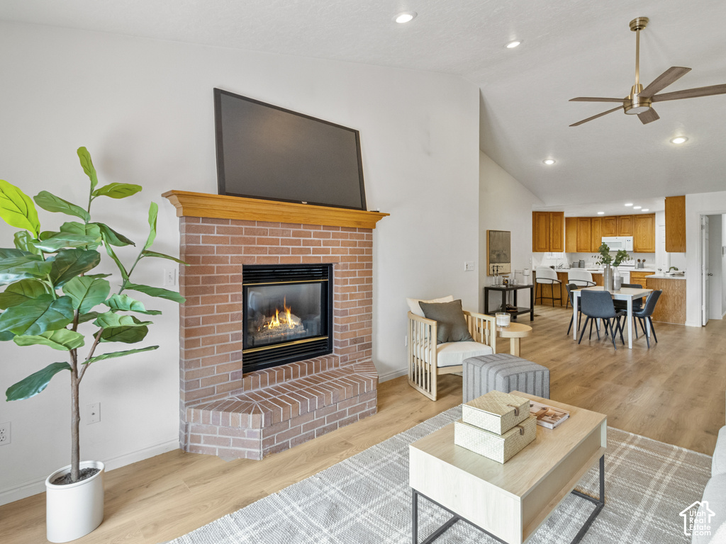 Living area with a brick fireplace and wood mantle, vaulted ceilings, and wood-finish flooring