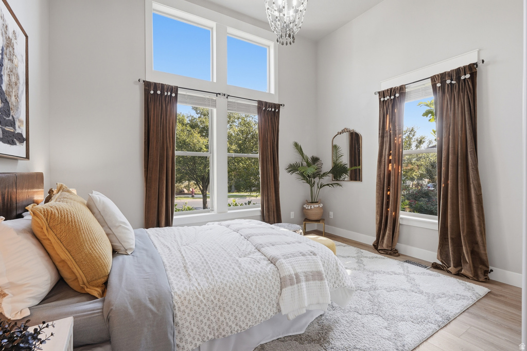 Interior space featuring high ceilings, a prominent chandelier, wood-finish flooring, and multiple large windows with transom elements