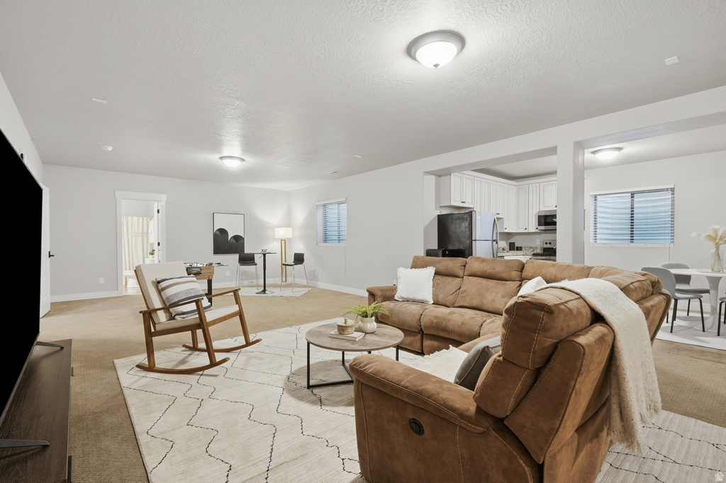 Spacious open-concept living area featuring light-toned carpeting and neutral wall tones