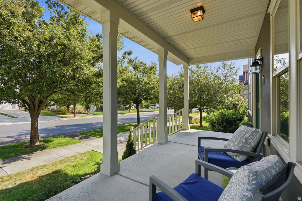 Inviting front porch featuring a concrete surface, white painted columns, and a coordinating white railing