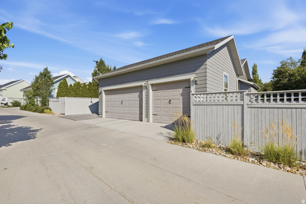 Two-car garage with panel-style doors and gray siding, featuring a gabled roofline