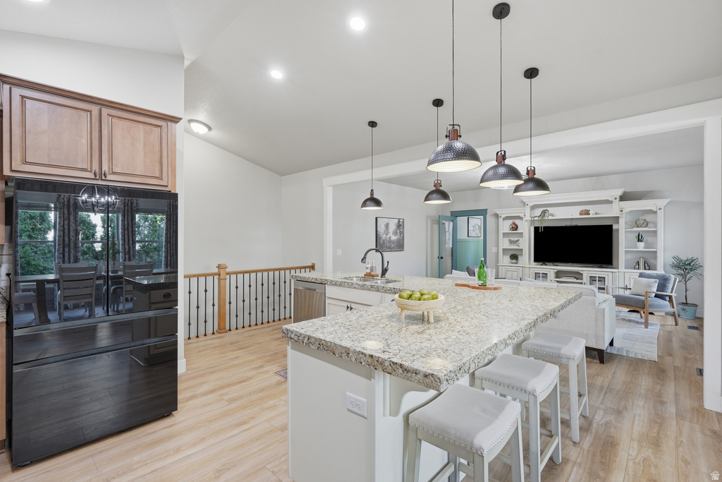 Open-concept kitchen and living area featuring a large island with a light-toned countertop, wood-finish flooring, and recessed lighting