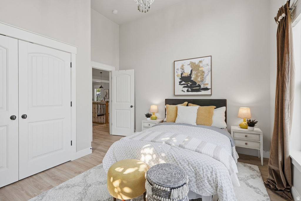 Bedroom featuring high vaulted ceilings with a chandelier, wood-finish flooring, and crisp white paneled doors