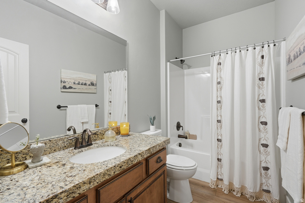 Bathroom featuring a vanity with a granite-style countertop, an undermount sink, and wood-finish cabinetry