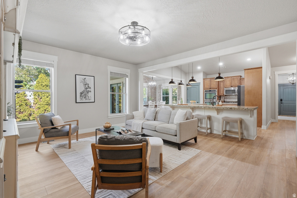 Open concept living space featuring light wood-finish flooring, a contemporary ceiling fan, and multiple windows providing natural illumination