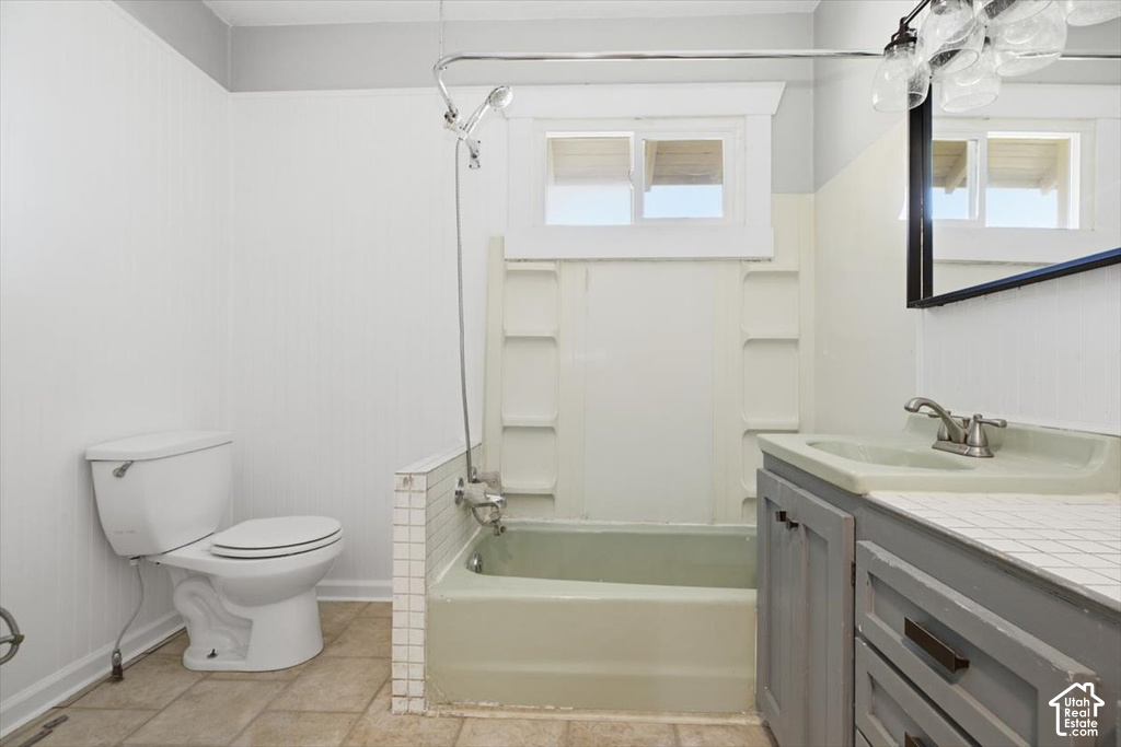 Bathroom featuring a bathtub with shower fixture, a single vanity with an integrated sink, a mirror, and tiled flooring