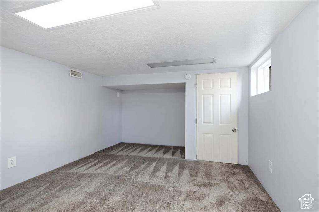 Spacious bonus room with neutral carpet flooring, recessed ceiling lighting, and abundant natural light from skylight and window