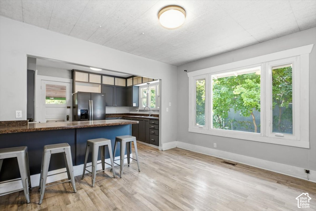 Open concept kitchen with dark cabinetry, stone-finish countertops, and wood-finish flooring