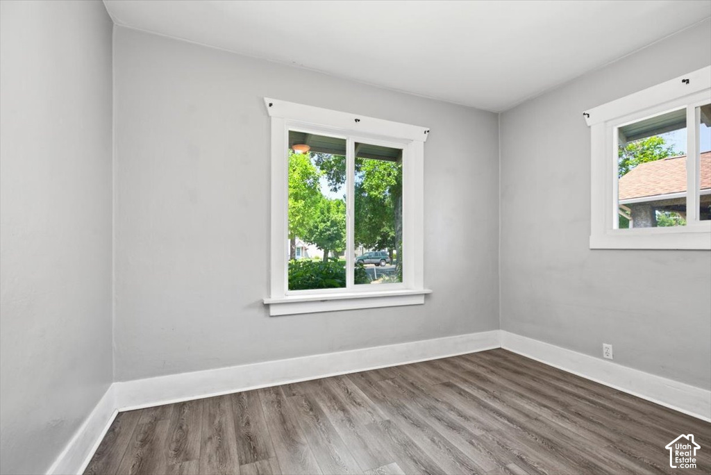 Wood-finish flooring, light gray wall paint, and multiple windows with white trim