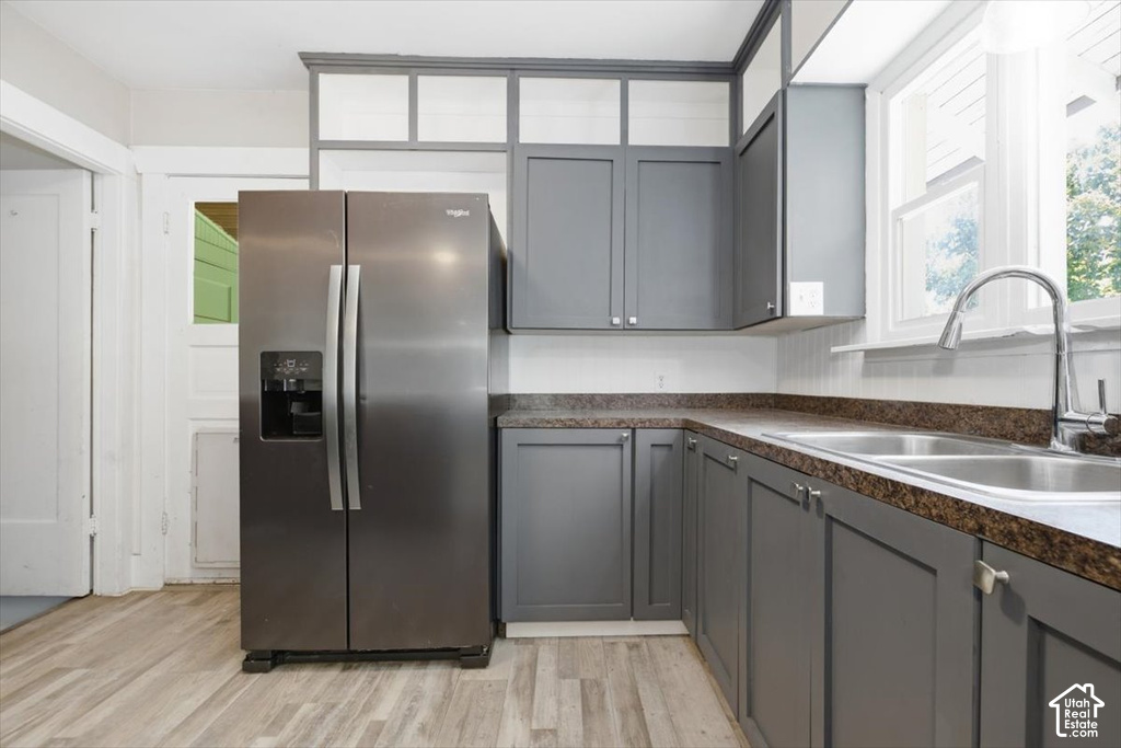 Modern kitchen featuring stainless steel side-by-side refrigerator, gray cabinetry with brushed metal hardware, granite countertops, undermount sink with contemporary faucet, and wood-finish flooring throughout