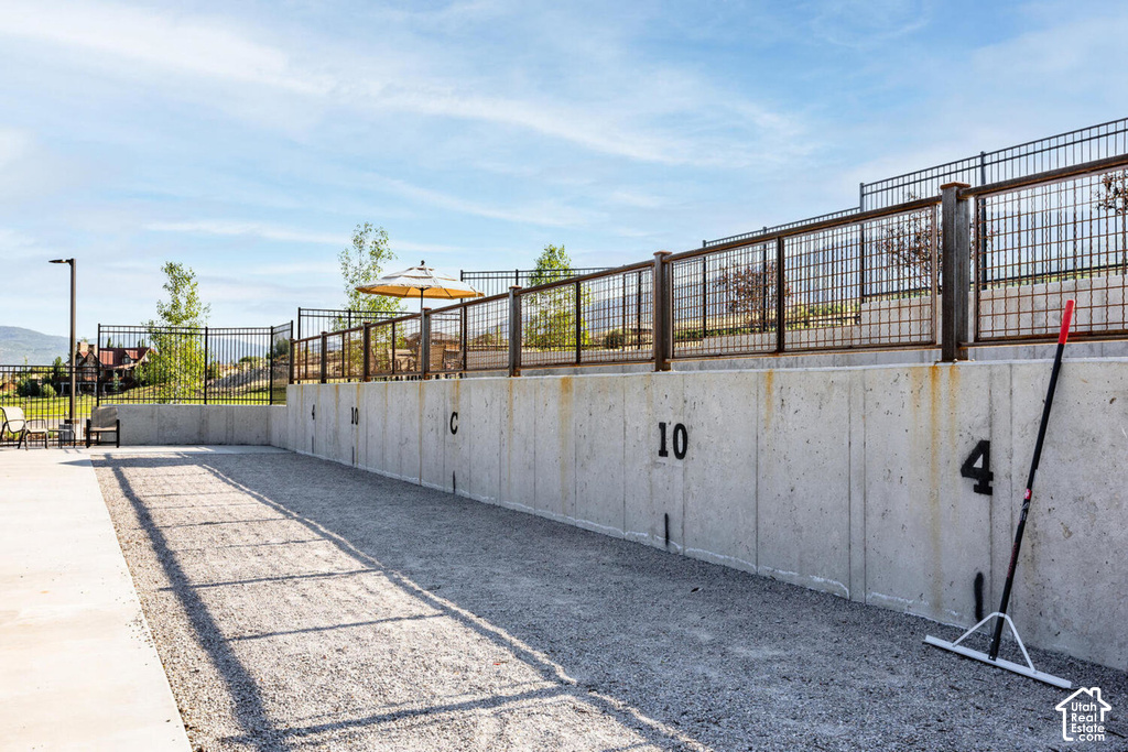 Bocce ball court featuring a concrete retaining wall, metal fencing, and a gravel playing surface