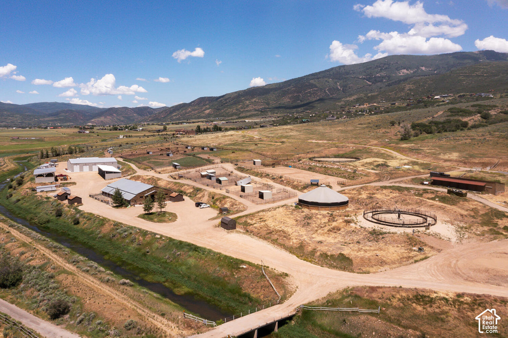 Expansive property featuring multiple outbuildings, fenced enclosures, a covered round pen, an outdoor round pen, and a meandering stream along the property boundary