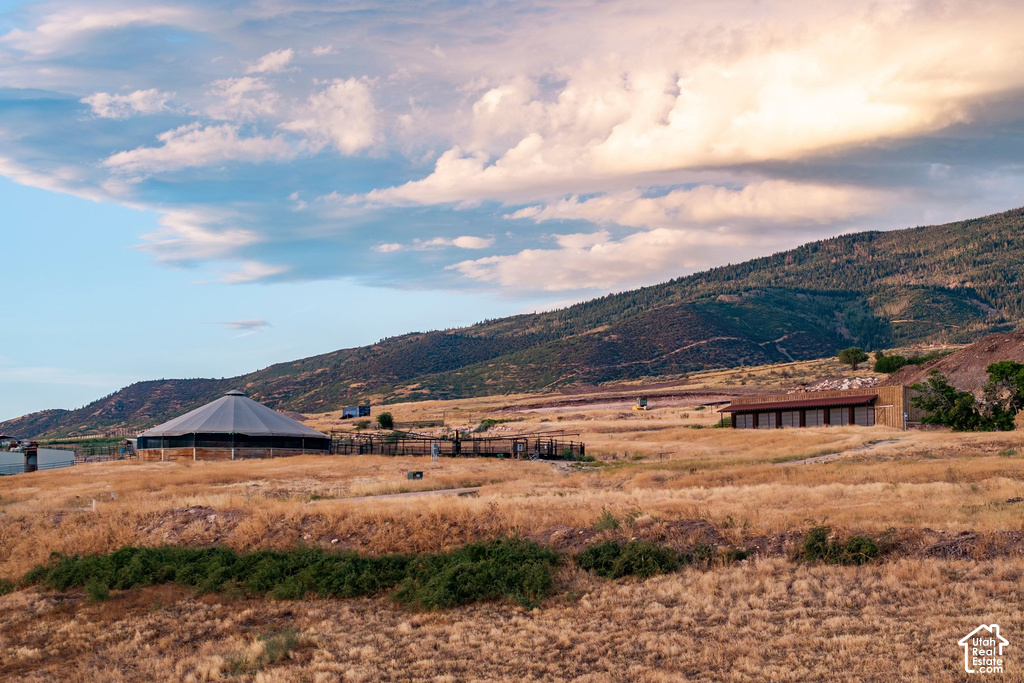 Expansive property featuring a large circular structure, a rectangular building with multiple windows, and a mountainous backdrop