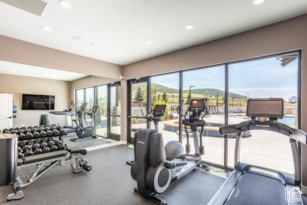 Dedicated fitness area featuring rubber flooring, recessed lighting, and expansive windows