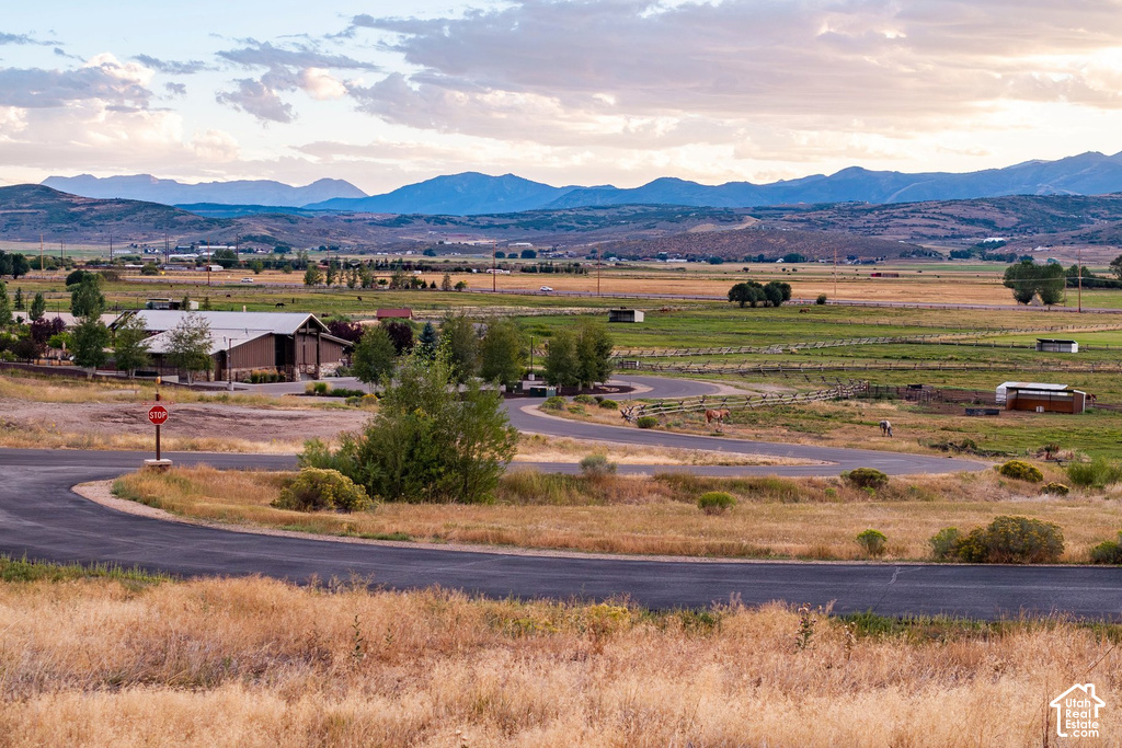Expansive rural setting with a winding paved road, agricultural fields, and distant mountain ranges