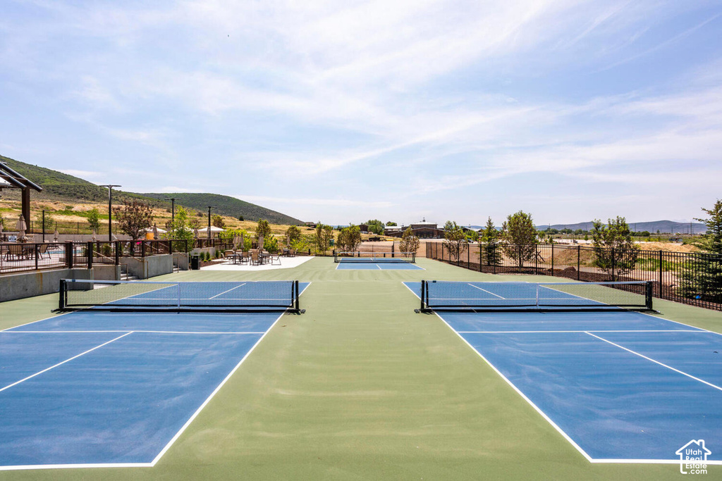 Multiple outdoor courts with blue and green surfacing, featuring black perimeter fencing
